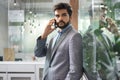 Handsome young business man talking on mobile phone in office. Royalty Free Stock Photo