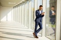 Young business man using mobile phone in the modern office hallway Royalty Free Stock Photo