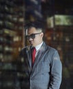 Young business man wearing suit and red tie with sunglasses giving a sophisticated look at night. Royalty Free Stock Photo