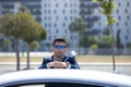 Handsome young businessman with beard and blue suit leaning on his white sports car. The man is wearing sunglasses. Business Royalty Free Stock Photo