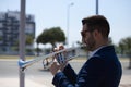 Handsome young businessman with a beard and a blue suit playing the trumpet. The man is a musician in his spare time and music is Royalty Free Stock Photo