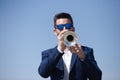 Handsome young businessman with a beard and a blue suit playing the trumpet. The man is a musician in his spare time and music is Royalty Free Stock Photo