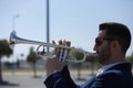 Handsome young businessman with a beard and a blue suit playing the trumpet. The man is a musician in his spare time and music is Royalty Free Stock Photo