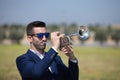 Handsome young businessman with a beard and a blue suit playing the trumpet. The man is a musician in his spare time and music is Royalty Free Stock Photo