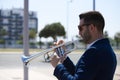 Handsome young businessman with a beard and a blue suit playing the trumpet. The man is a musician in his spare time and music is Royalty Free Stock Photo