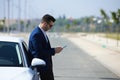 Handsome young businessman with beard and blue suit standing next to his white sports car. The man is wearing sunglasses and Royalty Free Stock Photo