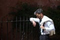 Handsome young businessman, bearded, in suit and tie, with jacket over his shoulder, leaning on a metal grille looking at the Royalty Free Stock Photo