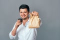 Handsome young businessman holding brown paper packet with take away food and cup of coffee. Business lunch fast food students