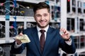 handsome young businessman holding stack of cash and bitcoin at cryptocurrency