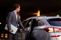 Handsome young businessman with laptop getting into luxury car Royalty Free Stock Photo