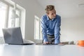 Handsome young businessman leaning on his office desk as he browses the digital tablet