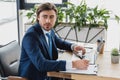 handsome young businessman looking away while writing on clipboard and using laptop Royalty Free Stock Photo