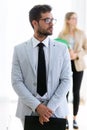 Handsome young businessman looking sideways with his partner behind in a hallway of they company. Royalty Free Stock Photo