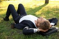 Handsome young businessman lying on green grass in park Royalty Free Stock Photo