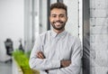 Handsome young businessman portrait. Cheerful self confident smiling man with crossed hands office. Royalty Free Stock Photo