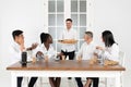 Handsome young businessman in shirt holding box with pizza in office