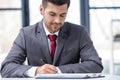 Handsome young businessman sitting at desk and writing in papers Royalty Free Stock Photo