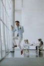 Young businessman with smartphone in a modern office jumping after receving a great news