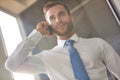 Handsome young businessman smiling while talking on smart phone while standing in new office Royalty Free Stock Photo