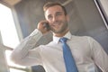 Handsome young businessman smiling while talking on smart phone while standing in new office Royalty Free Stock Photo