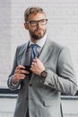 handsome young businessman in suit and eyeglasses holding smartphone Royalty Free Stock Photo