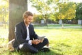 Handsome young businessman with tablet PC resting on green grass in park Royalty Free Stock Photo