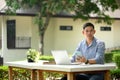 Handsome young businessman using laptop outdoors, holding smartphone and looking away Royalty Free Stock Photo