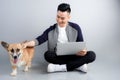 Handsome young businessman is using laptop while sitting with his dog on floor Royalty Free Stock Photo