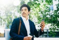 Handsome young businessman using smartphone for listining music while walking in city park.Horizontal,blurred background Royalty Free Stock Photo