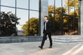 Handsome young businessman walking outdoors at the street talking by mobile phone Royalty Free Stock Photo
