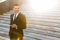 Handsome young businessman walking outdoors at the street using mobile phone Royalty Free Stock Photo