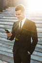 Handsome young businessman walking outdoors at the street using mobile phone Royalty Free Stock Photo