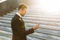 Handsome young businessman walking outdoors at the street using mobile phone Royalty Free Stock Photo