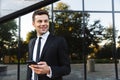 Handsome young businessman walking outdoors at the street using mobile phone Royalty Free Stock Photo