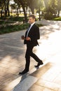 Handsome young businessman walking outdoors at the street using mobile phone Royalty Free Stock Photo