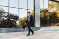 Handsome young businessman walking outdoors at the street using mobile phone Royalty Free Stock Photo