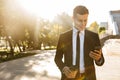 Handsome young businessman walking outdoors at the street using mobile phone Royalty Free Stock Photo