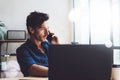 Handsome young businessman working at sunny work place on laptop.Elegant Man using smartphone while sitting at the Royalty Free Stock Photo