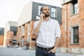 Handsome young caucasian businessman talking on mobile phone while walking on city street. Royalty Free Stock Photo