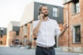 Handsome young caucasian businessman talking on mobile phone while walking on city street. Royalty Free Stock Photo