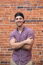 Handsome Young Caucasian Man with Cellphone and Backwards Hat Smiling for Portraits in Front of Textured Brick Wall Outside Royalty Free Stock Photo