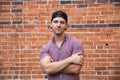 Handsome Young Caucasian Man with Cellphone and Backwards Hat Smiling for Portraits in Front of Textured Brick Wall Outside Royalty Free Stock Photo