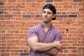 Handsome Young Caucasian Man with Cellphone and Backwards Hat Smiling for Portraits in Front of Textured Brick Wall Outside Royalty Free Stock Photo