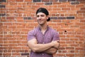 Handsome Young Caucasian Man with Cellphone and Backwards Hat Smiling for Portraits in Front of Textured Brick Wall Outside Royalty Free Stock Photo