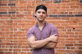 Handsome Young Caucasian Man with Cellphone and Backwards Hat Smiling for Portraits in Front of Textured Brick Wall Outside Royalty Free Stock Photo