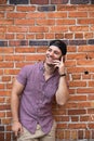 Handsome Young Caucasian Man with Cellphone and Backwards Hat Smiling for Portraits in Front of Textured Brick Wall Outside Royalty Free Stock Photo
