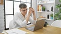 Handsome young caucasian man, confident worker smiling at his desk in the office, enjoying morning espresso while working online Royalty Free Stock Photo