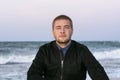 Handsome young Caucasian man looks at camera on seashore in evening