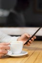 Handsome young caucasian man sitting at cafe using mobile phone and having coffee. Caucasian male with cup of coffee and Royalty Free Stock Photo
