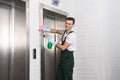 handsome young cleaner washing elevator and smiling Royalty Free Stock Photo